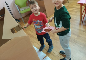 zadowoleni chłopcy podczas malowania domku z piernika